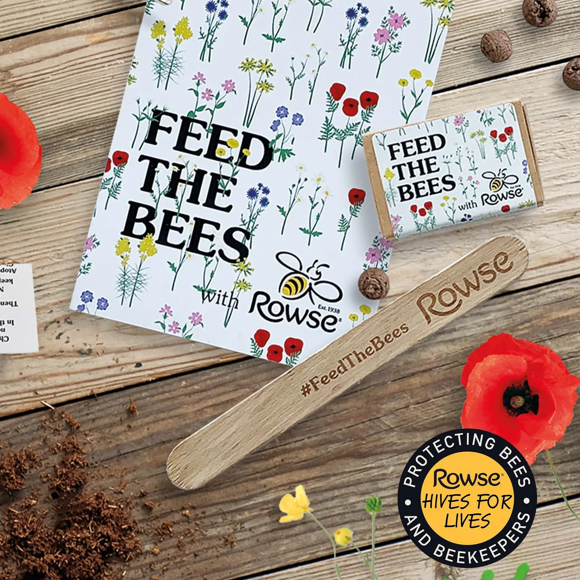Feed the Bees with Rowse seed packets laid out on wood with poppies