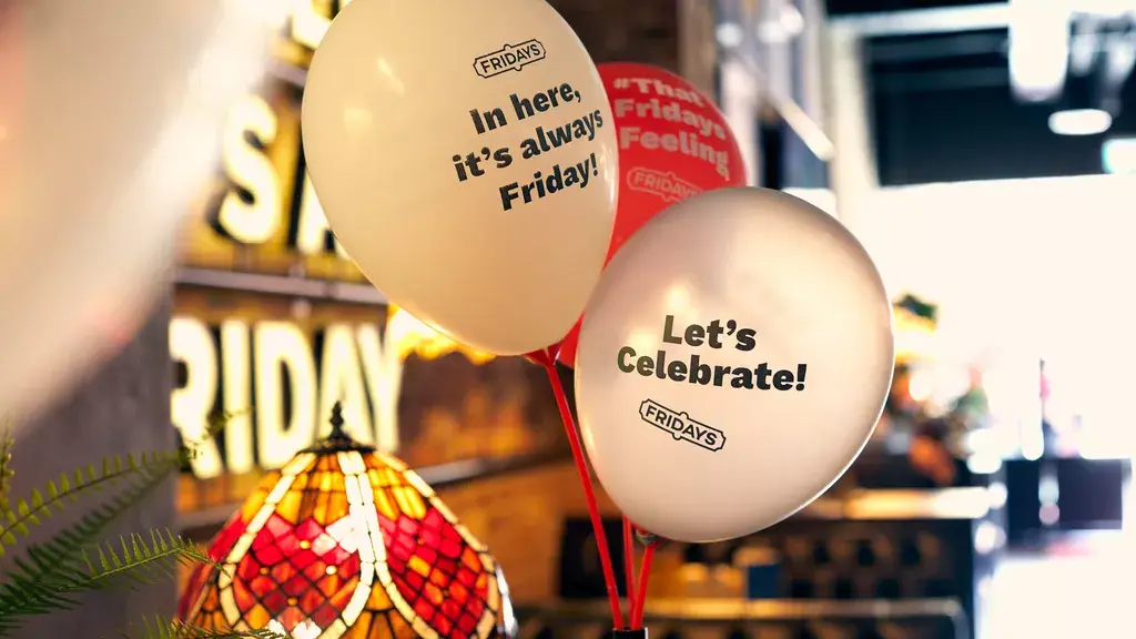 Balloons reading "In here, it's always Friday" and "Let's celebrate" in a restaurant