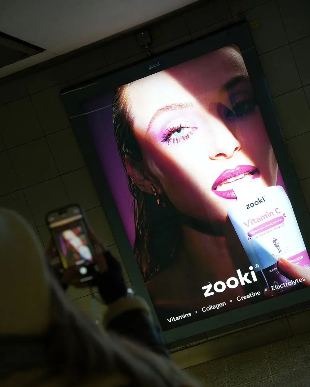 A Zooki Vitamin C poster being photographed on a phone